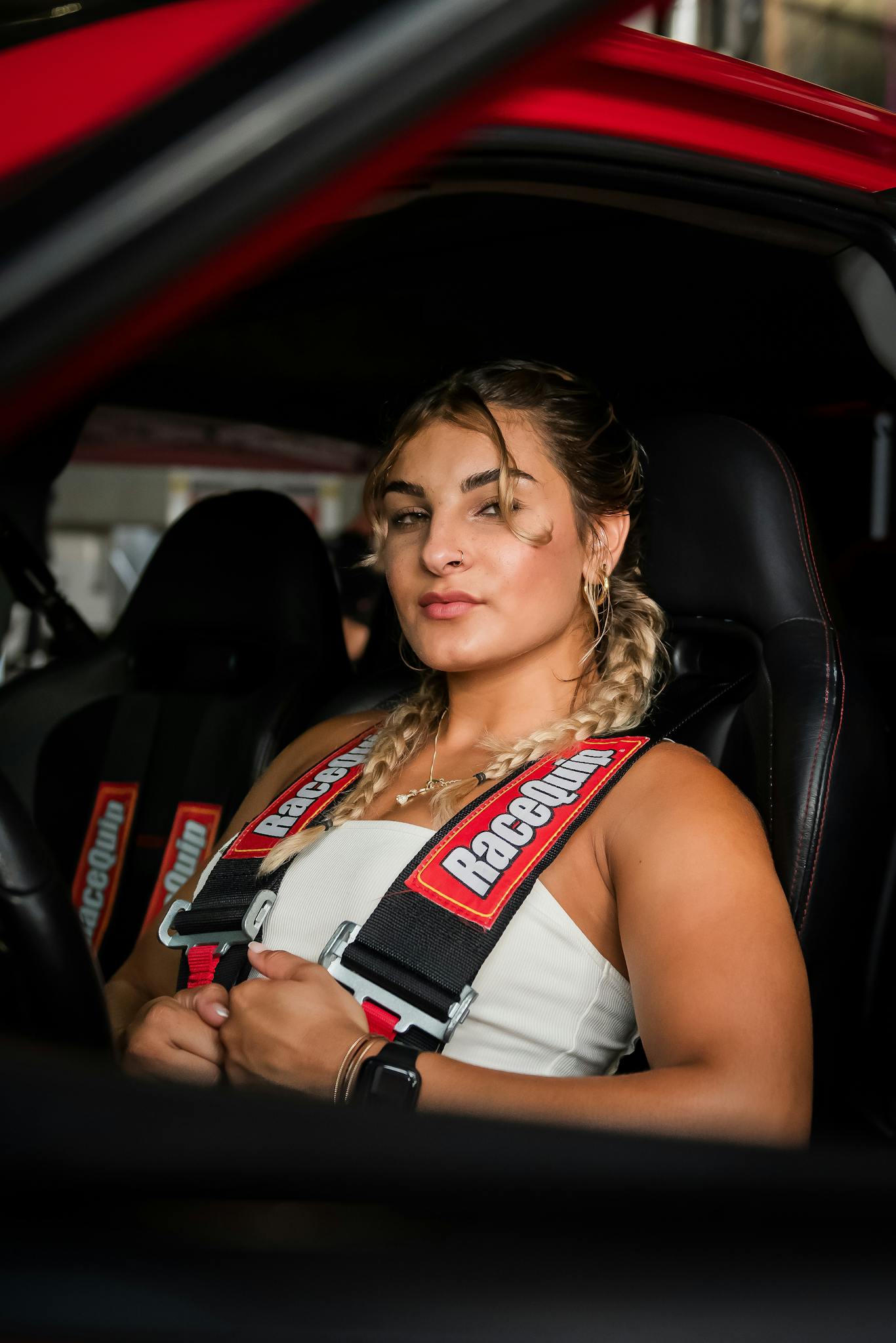 Blonde woman sitting confidently in a sports car, fitted with a safety harness in Orlando, FL.