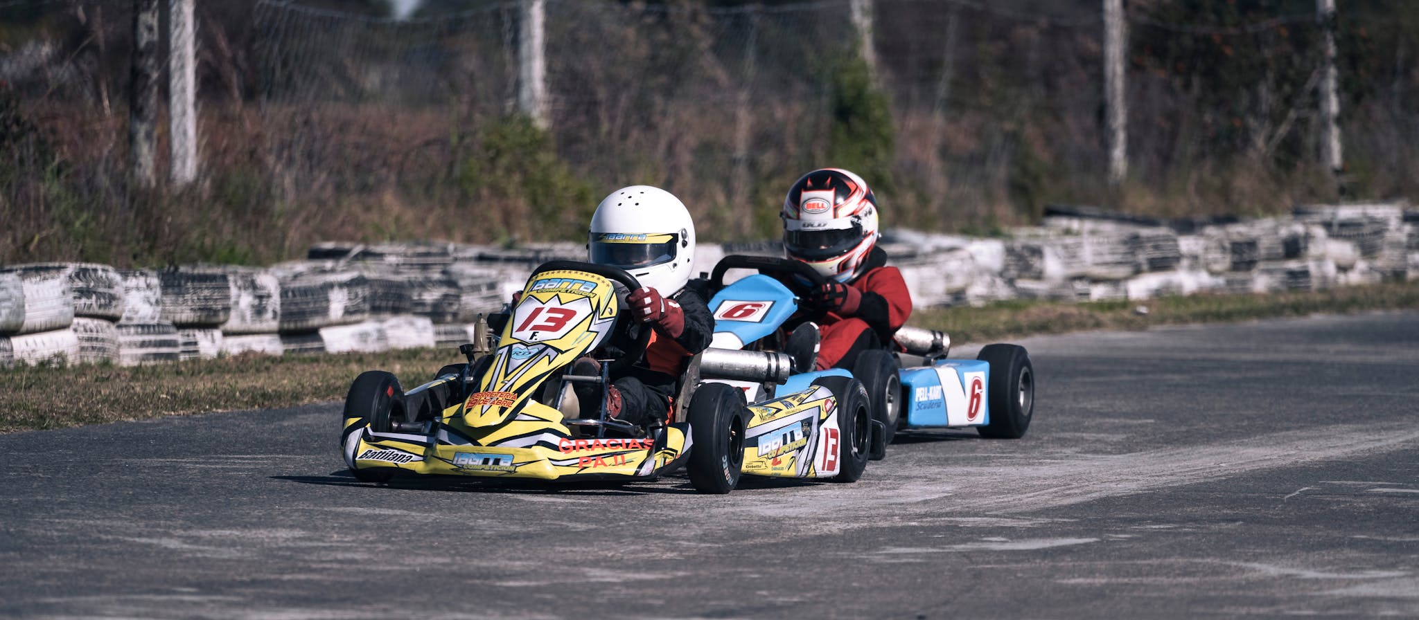 Two go-karts racing fiercely on an outdoor track showcasing speed and competition.